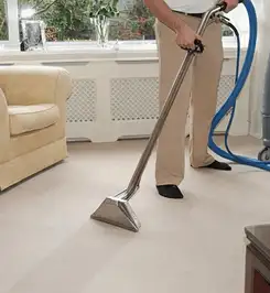 Professional carpet cleaner using a hot-water extraction wand and hose machine in a living room in Columbia, MO.