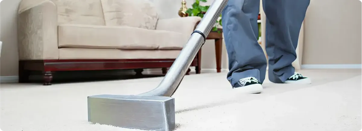 Carpet cleaning technician using a hot-water extraction wand on a light-colored carpet in a living room, Columbia, MO.