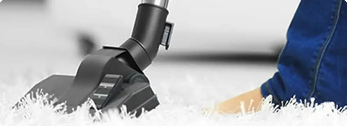 Close-up of a professional vacuuming a white carpet in Hartsburg.